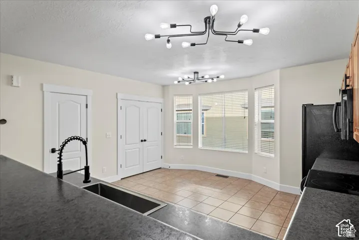 Kitchen with black countertop, stainless steel sink, and a black gooseneck faucet