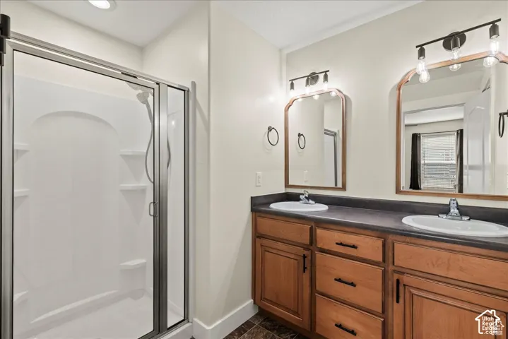 Master bathroom. Double vanity with wood-finish cabinetry, dual undermount sinks, and a dark countertop