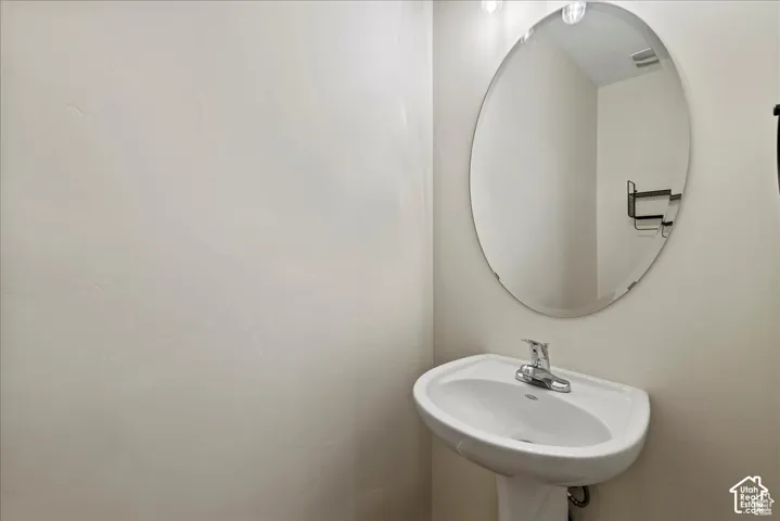 Pedestal sink with a polished chrome faucet and an oval wall mirror