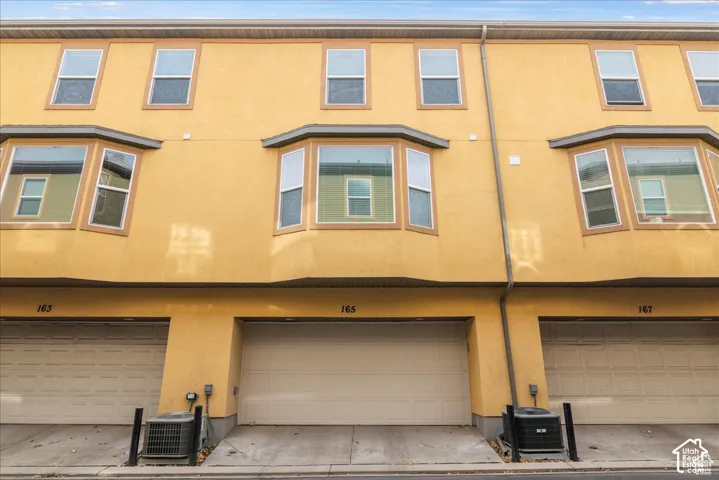 Stucco exterior with multiple bay windows and individual garage doors