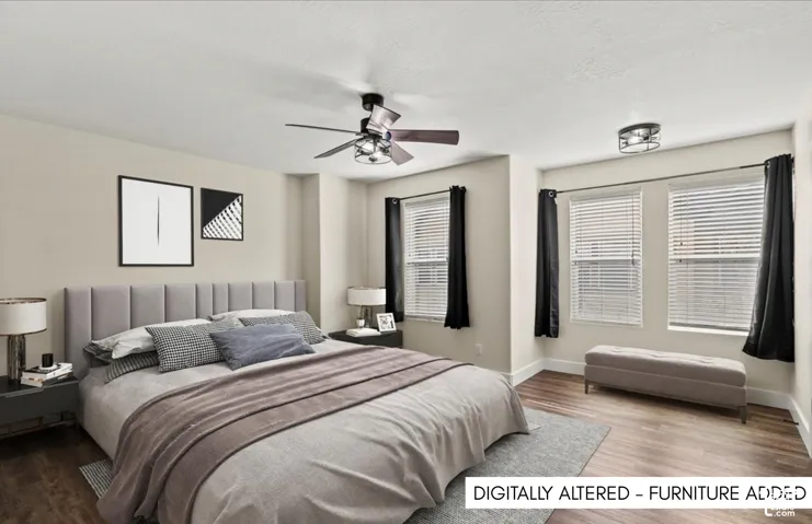 Master bedroom. Wood-finish flooring, two large windows with blinds, ceiling fan with integrated lighting, and a flush mount light fixture