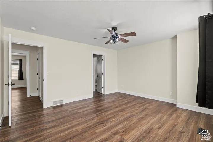Master bedroom. Wood-finish flooring, ceiling fan with integrated lighting, white trim and baseboards, and neutral wall paint