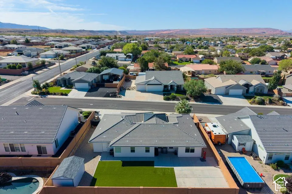 Single-story residential property featuring a gray tile roof and a fenced backyard with artificial turf and a shed