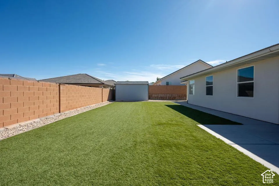 Expansive artificial turf lawn bordered by a block wall and concrete patio