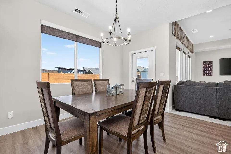 Dining area with wood-finish flooring, a large window, and a modern chandelier