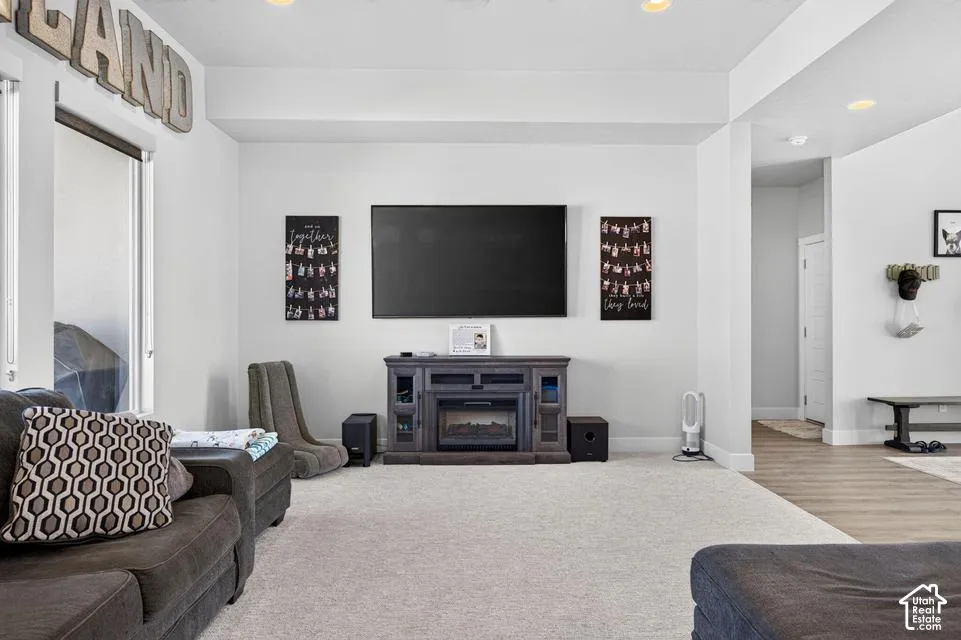 Recessed lighting, light-colored carpeting, and a built-in electric fireplace with media console