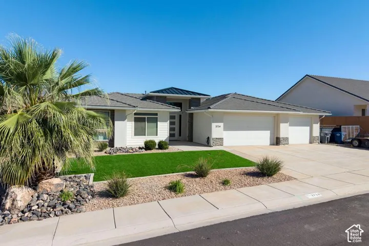 Modern exterior featuring a two-car garage, manicured lawn, and a large palm tree