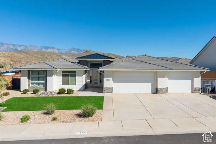 Modern exterior with a light-colored stucco finish, stone accents, and a multi-level gray tile roof