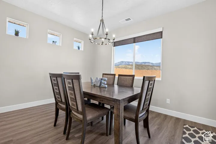 Formal dining area with large picture window, mountain scenery, wood-finish flooring, and a decorative chandelier