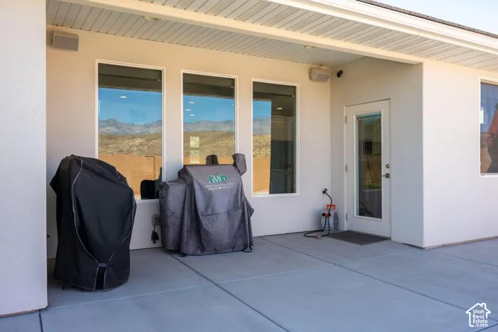 Covered patio area with a glass-paneled exterior door, three large windows, and a structured overhang