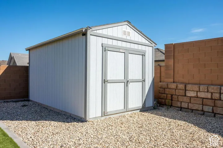 Freestanding white storage shed with gray trim, double doors, and a gable roof