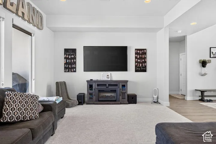 Recessed lighting, light-colored carpeting, and a built-in electric fireplace with media console