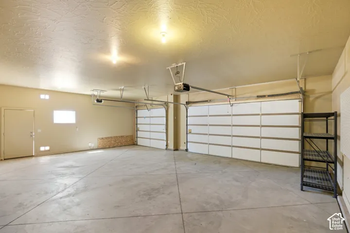 Spacious garage with concrete flooring, two sectional garage doors, and overhead lighting