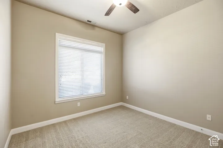 Recessed window with white blinds, neutral carpet flooring, and a ceiling fan with integrated lighting