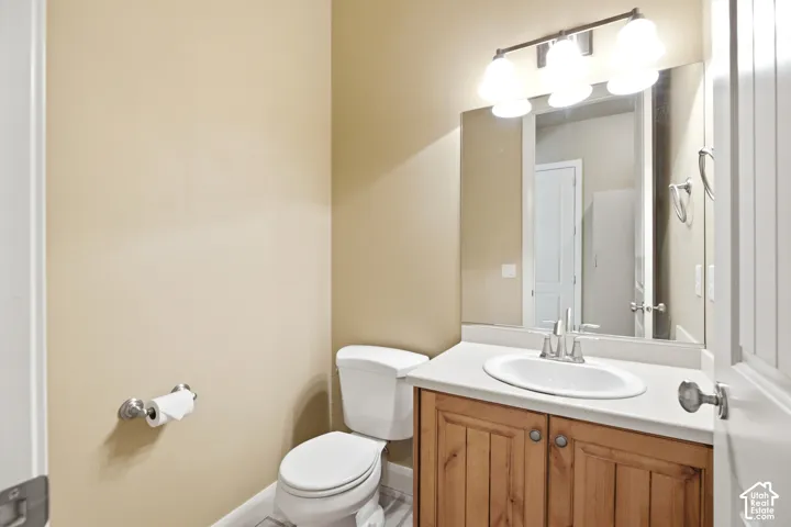 Vanity with wood-finish cabinetry, white countertop, and integrated sink