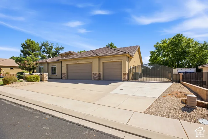 Stucco exterior with stone accents, concrete driveway, two-car garage, and a gated side yard