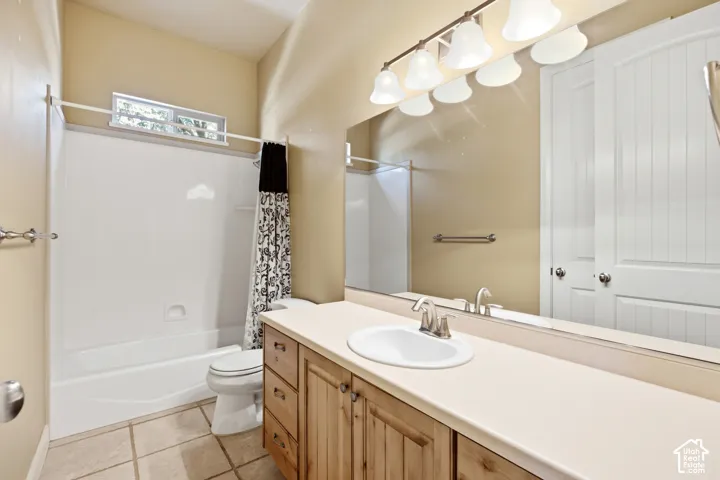 Tiled flooring with a wood-finish vanity, an integrated sink, and a full-width mirror