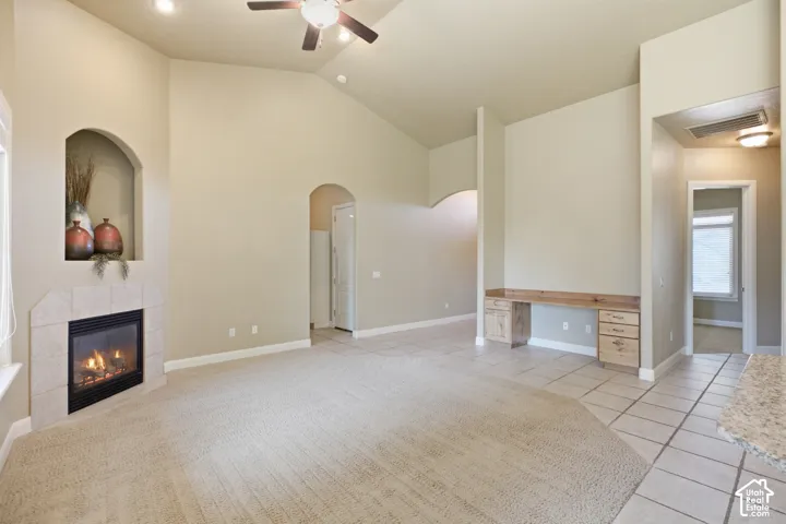 Vaulted ceiling with a ceiling fan, recessed lighting, and a corner fireplace with a tiled surround