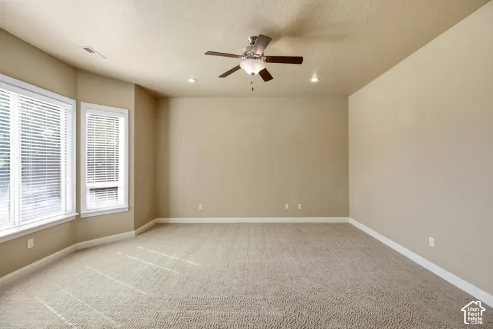 Spacious room featuring neutral wall tones, carpet flooring, a ceiling fan with integrated lighting, and recessed ceiling lighting