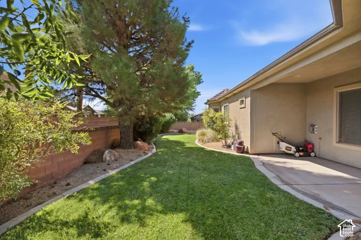 Expansive backyard featuring a manicured lawn, mature trees, and a concrete patio