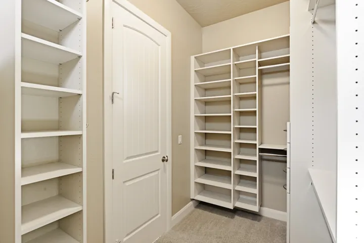 Integrated custom shelving, built-in hanging rods, and light-toned carpet