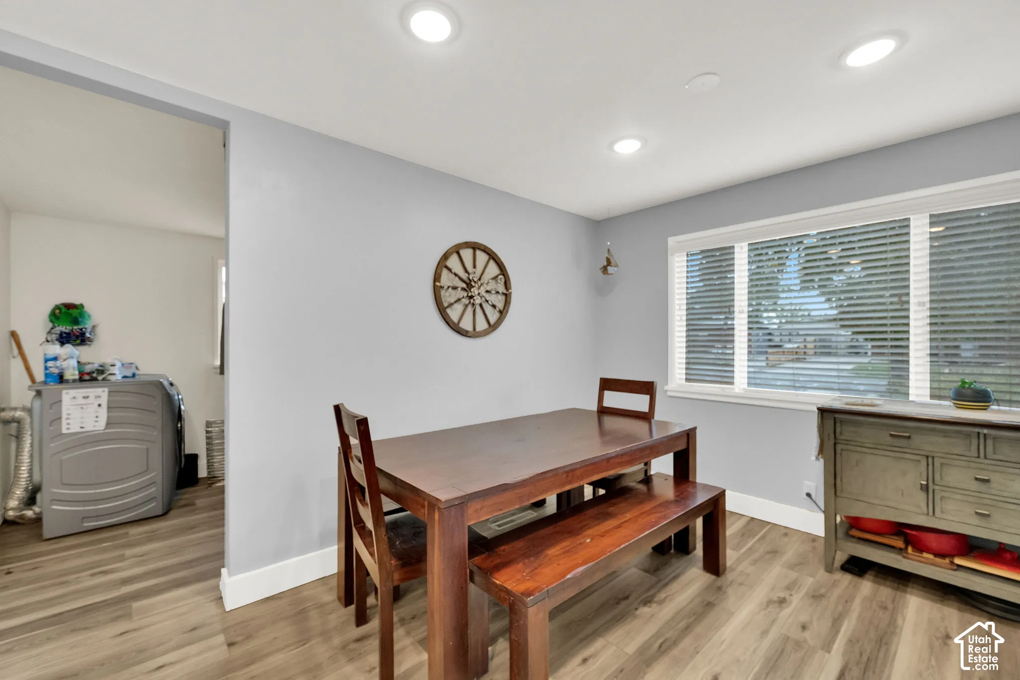 Recessed ceiling lighting, large window with blinds, wood-finish flooring, and light gray wall paint