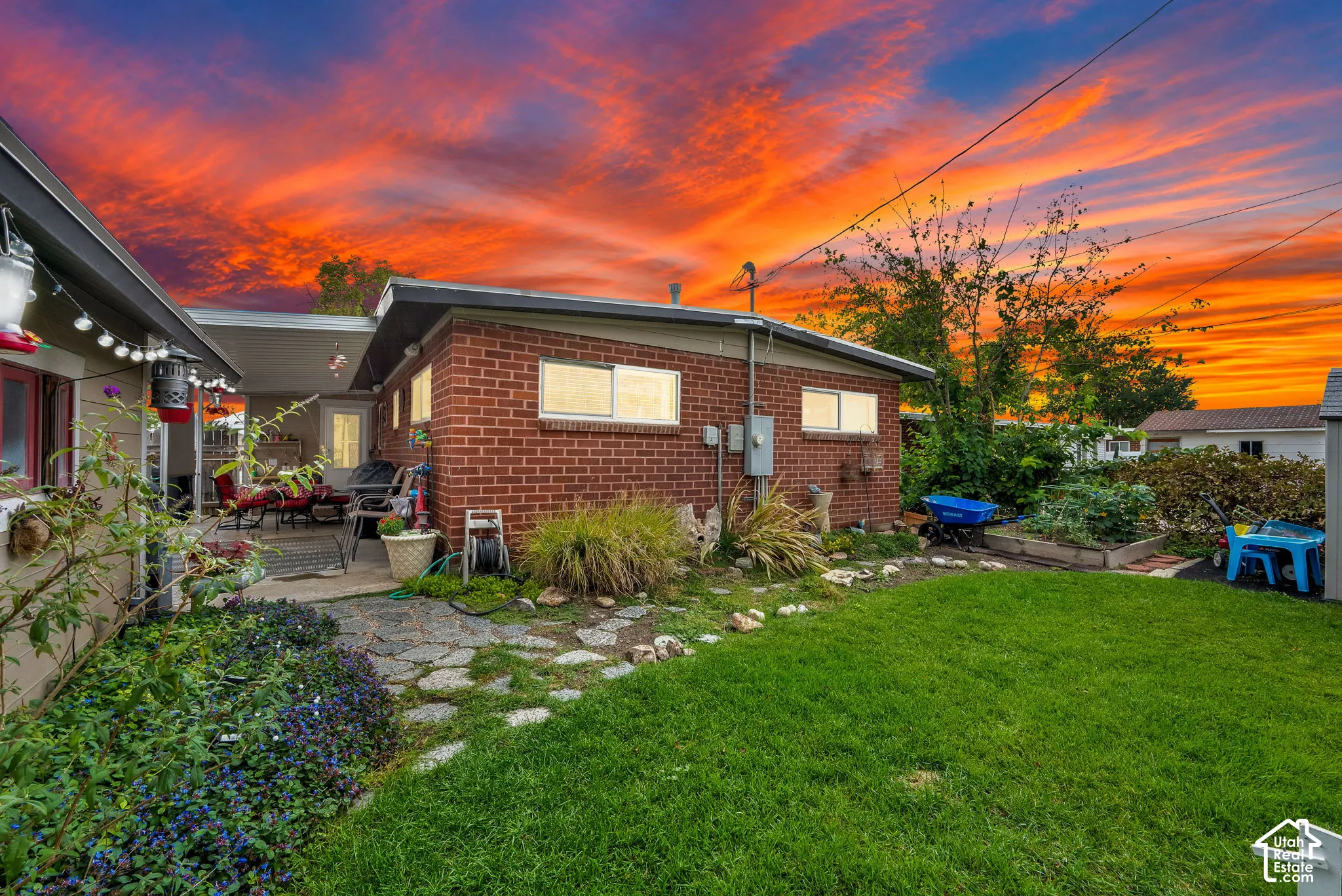 Rear exterior featuring a covered patio, brick siding, and a manicured lawn