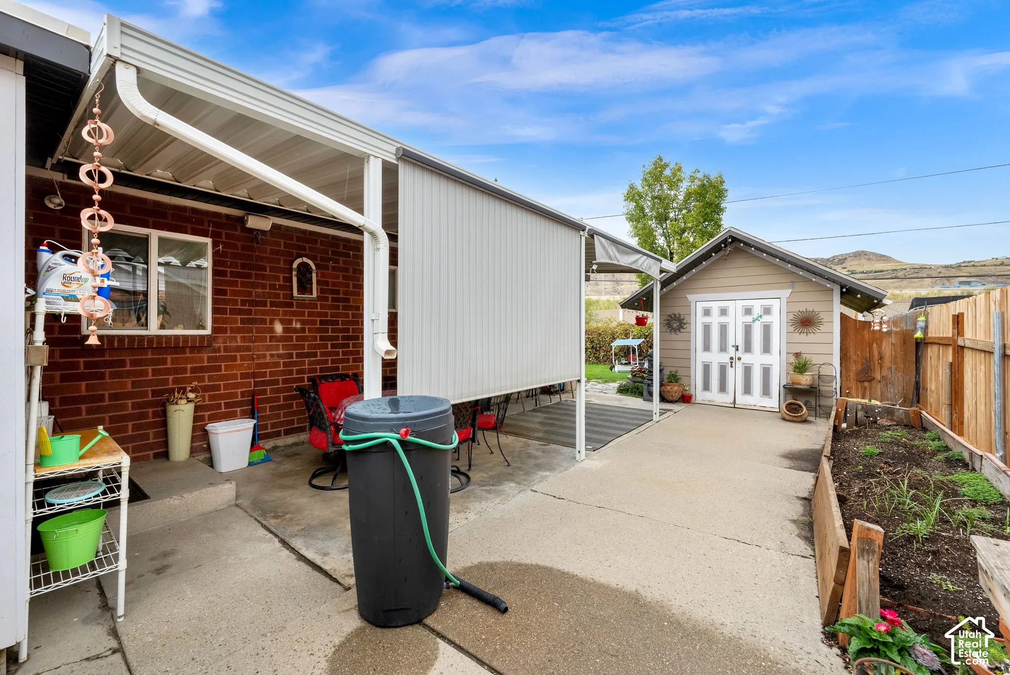 Brick exterior with a covered patio, concrete paving, and a detached shed