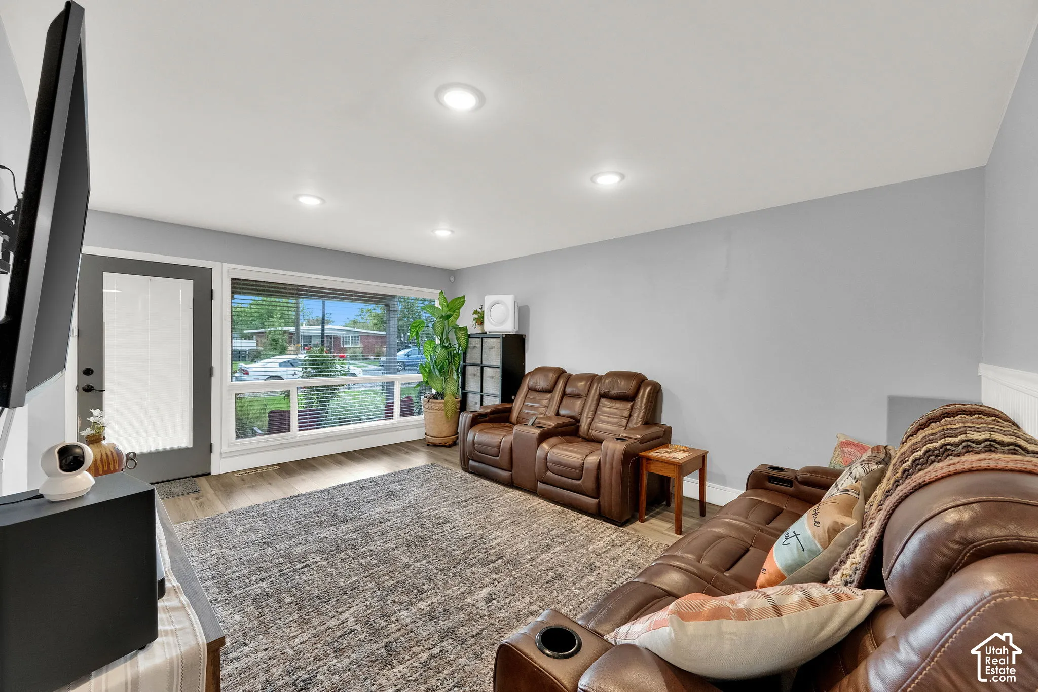 Living area featuring wood-finish flooring, recessed lighting, and expansive windows with horizontal blinds