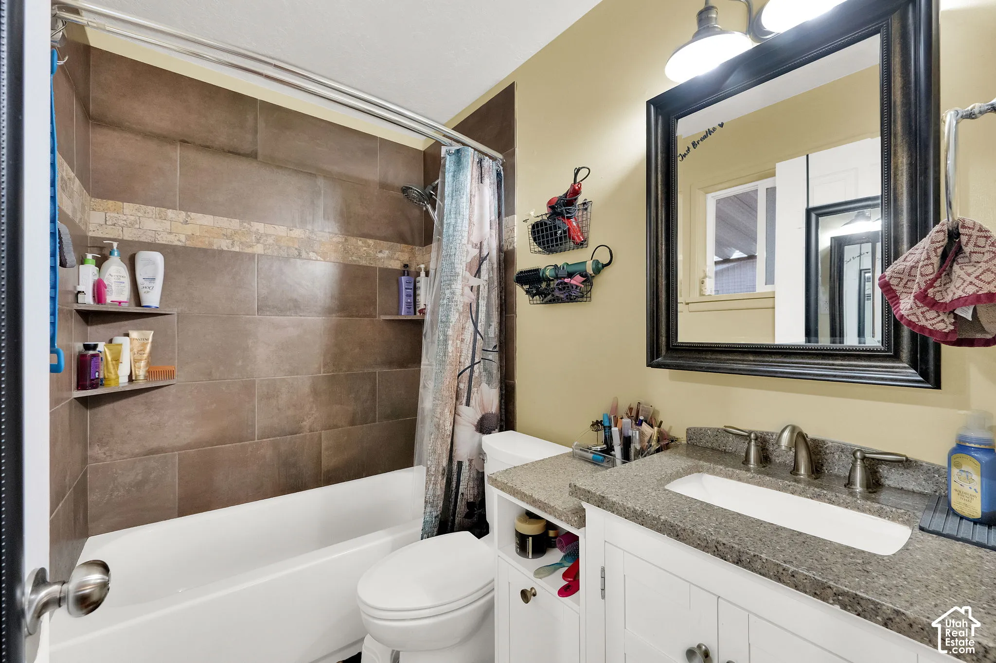 Tub-shower combination with brown tile surround and decorative tile band
