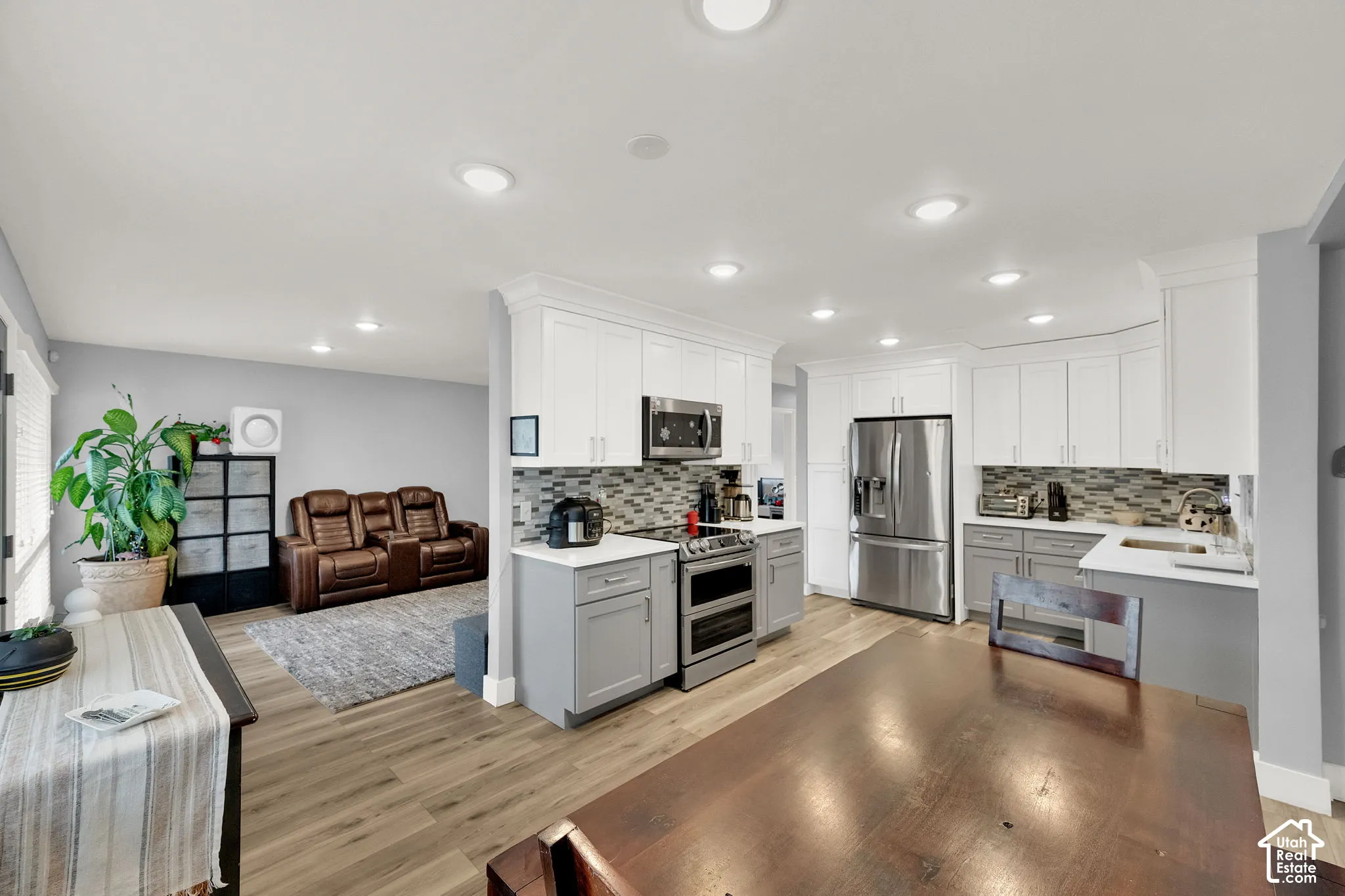 Modern kitchen featuring stainless steel appliances, two-tone cabinetry, and a mosaic tile backsplash