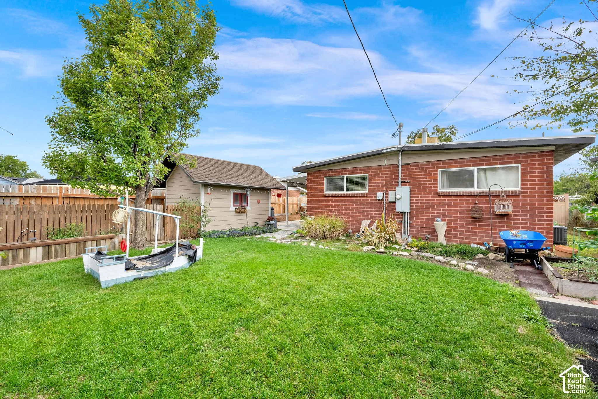 Expansive backyard featuring a meticulously manicured lawn, mature shade trees, and established landscaping beds