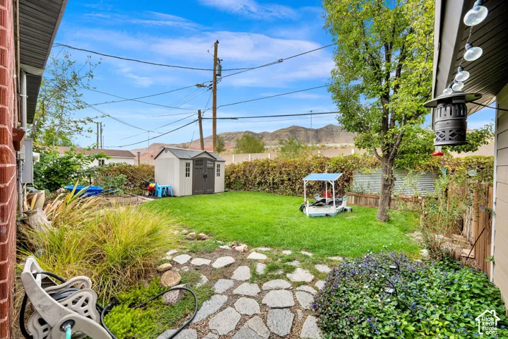 Expansive backyard featuring a manicured lawn, mature trees, and a stone pathway