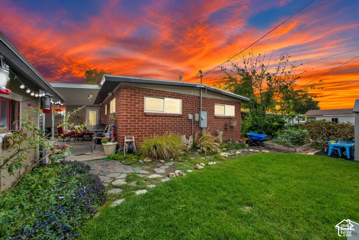 Rear exterior featuring a covered patio, brick siding, and a manicured lawn