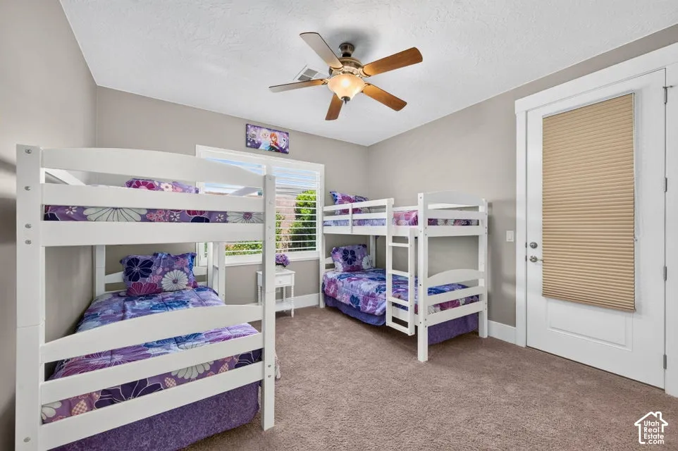 Carpeted room featuring a ceiling fan with light fixture, neutral wall paint, and white trim
