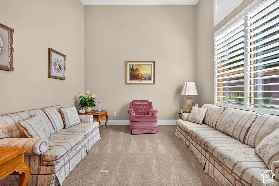 Vaulted ceilings, large windows with plantation shutters, neutral wall tones, and carpet flooring