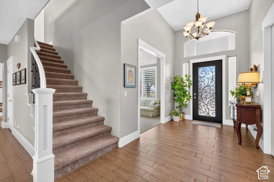 Vaulted entry featuring a decorative glass front door, wood-finish flooring, and a curved staircase with carpeted treads and an iron railing
