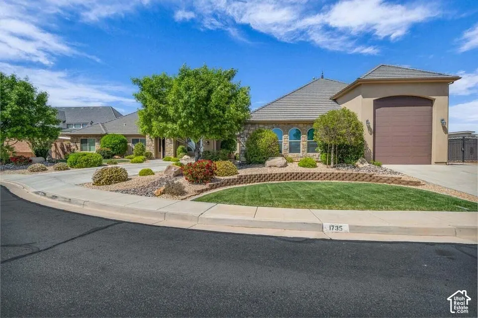 Stucco and stone exterior with arched windows, a tiled roof, and a two-car garage