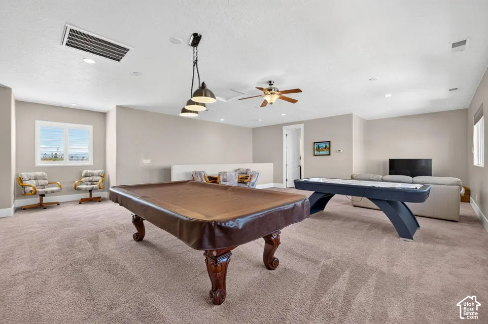 Spacious carpeted room featuring recessed lighting, a ceiling fan, and multiple windows