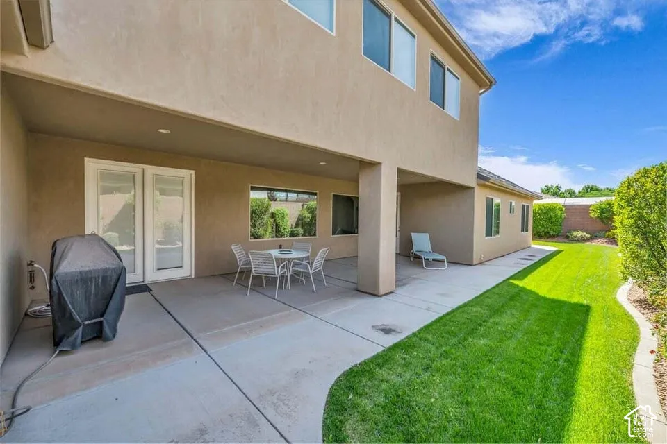 Ground-level covered patio with recessed lighting, direct outdoor access via French doors, and a manicured lawn border