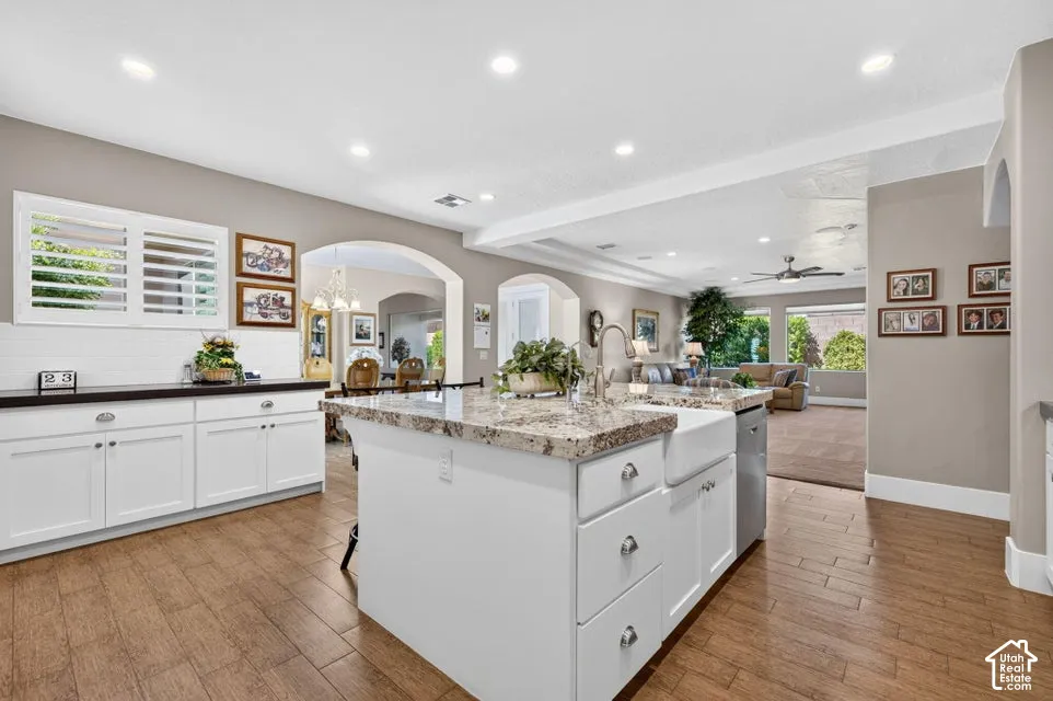 Kitchen featuring wood-finish flooring, white cabinetry, a spacious island with a farm sink, and recessed lighting