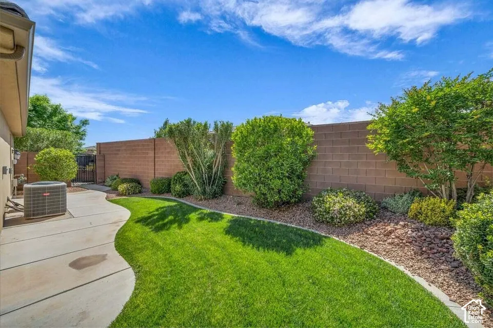 Expansive backyard featuring a manicured lawn, curved concrete pathway, and a perimeter wall with mature landscaping