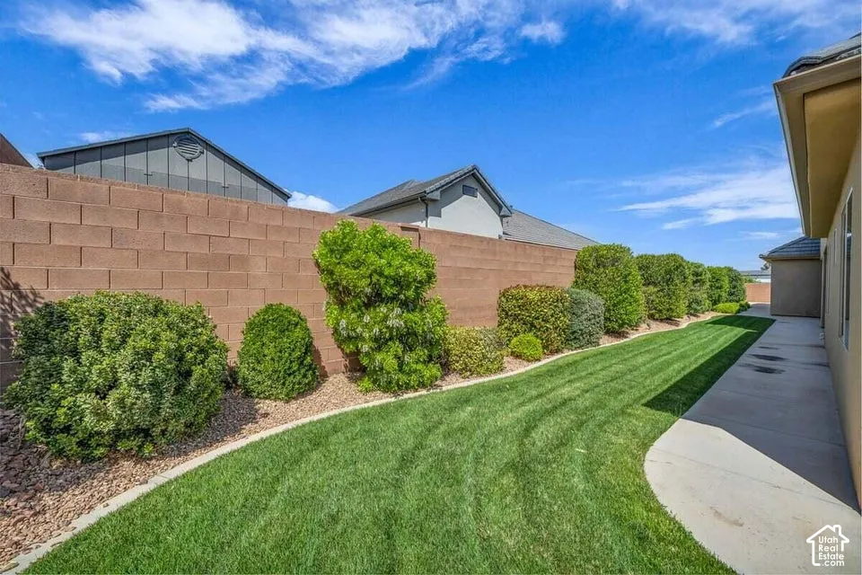 Expansive side yard featuring a manicured lawn, decorative gravel, and a variety of established shrubs