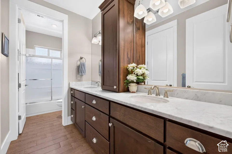 Dual sink vanity with wood-finish cabinetry, light-toned countertop, and undermount sinks