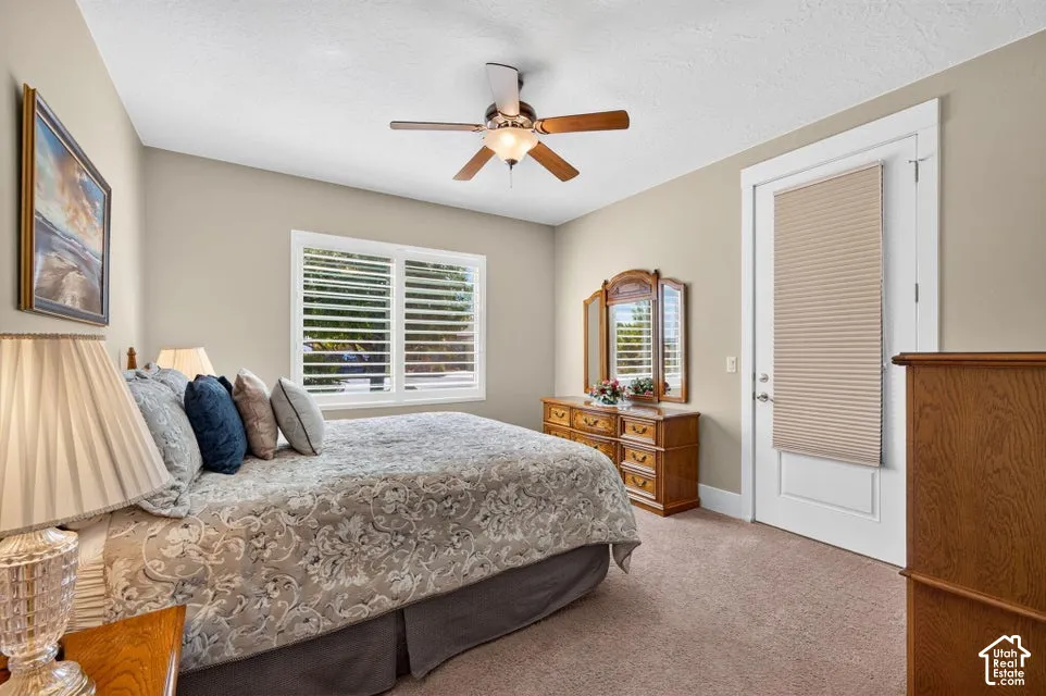 Carpeted room featuring a ceiling fan with integrated lighting, a window with louvered shutters, and a white door with a cellular shade