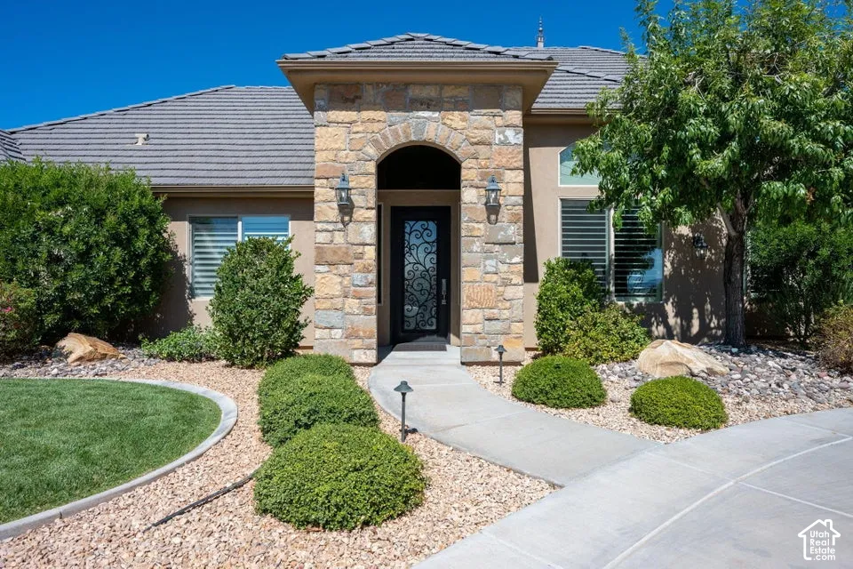 Stone facade entry with an arched doorway and decorative iron-detailed front door