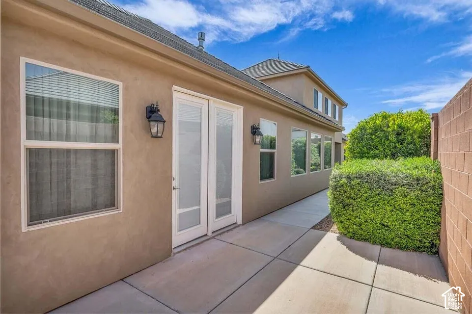 Stucco exterior with multiple windows, double glass doors, and exterior lighting fixtures