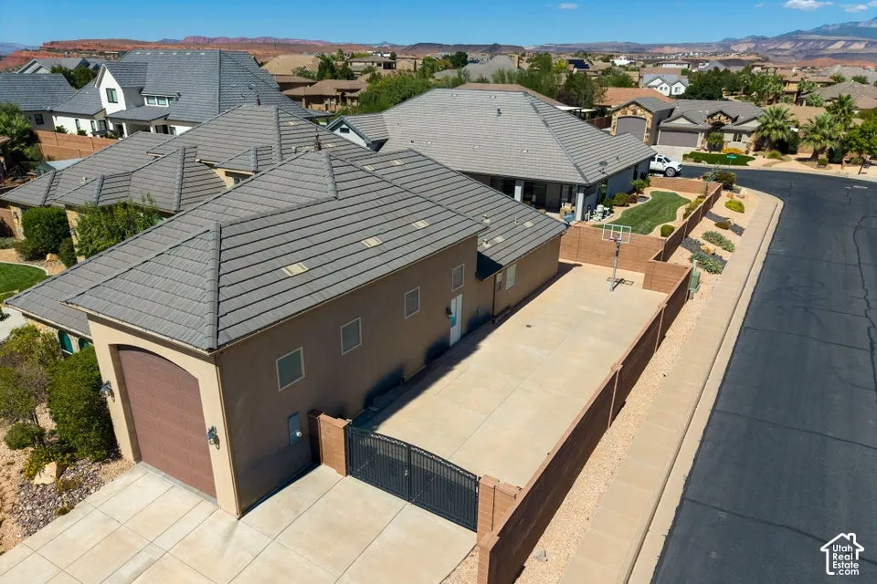 Terracotta tile roofing with multiple skylights, stucco exterior with an arched garage door, gated concrete driveway, and a basketball hoop
