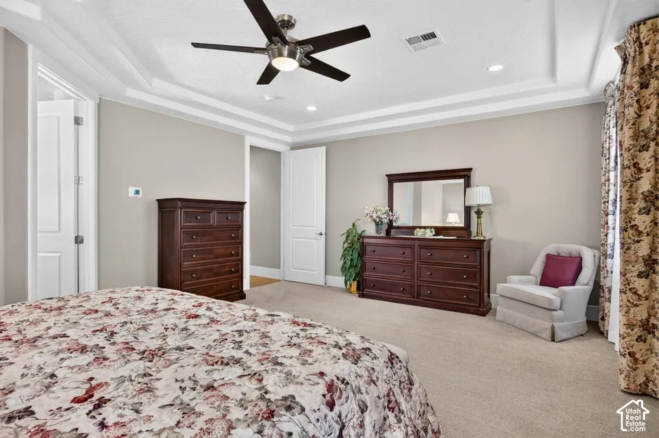 Tray ceiling with recessed lighting, ceiling fan, and light neutral wall color