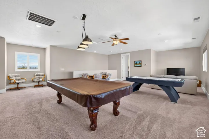 Spacious carpeted room featuring recessed lighting, a ceiling fan, and multiple windows